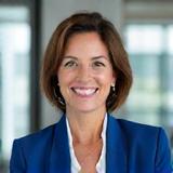 Porträt von Dr. Elena Schmidt, eine erfahrene Dozentin der Wivara Führung, vor einem leicht unscharfen modernen Klassenzimmer-Hintergrund.